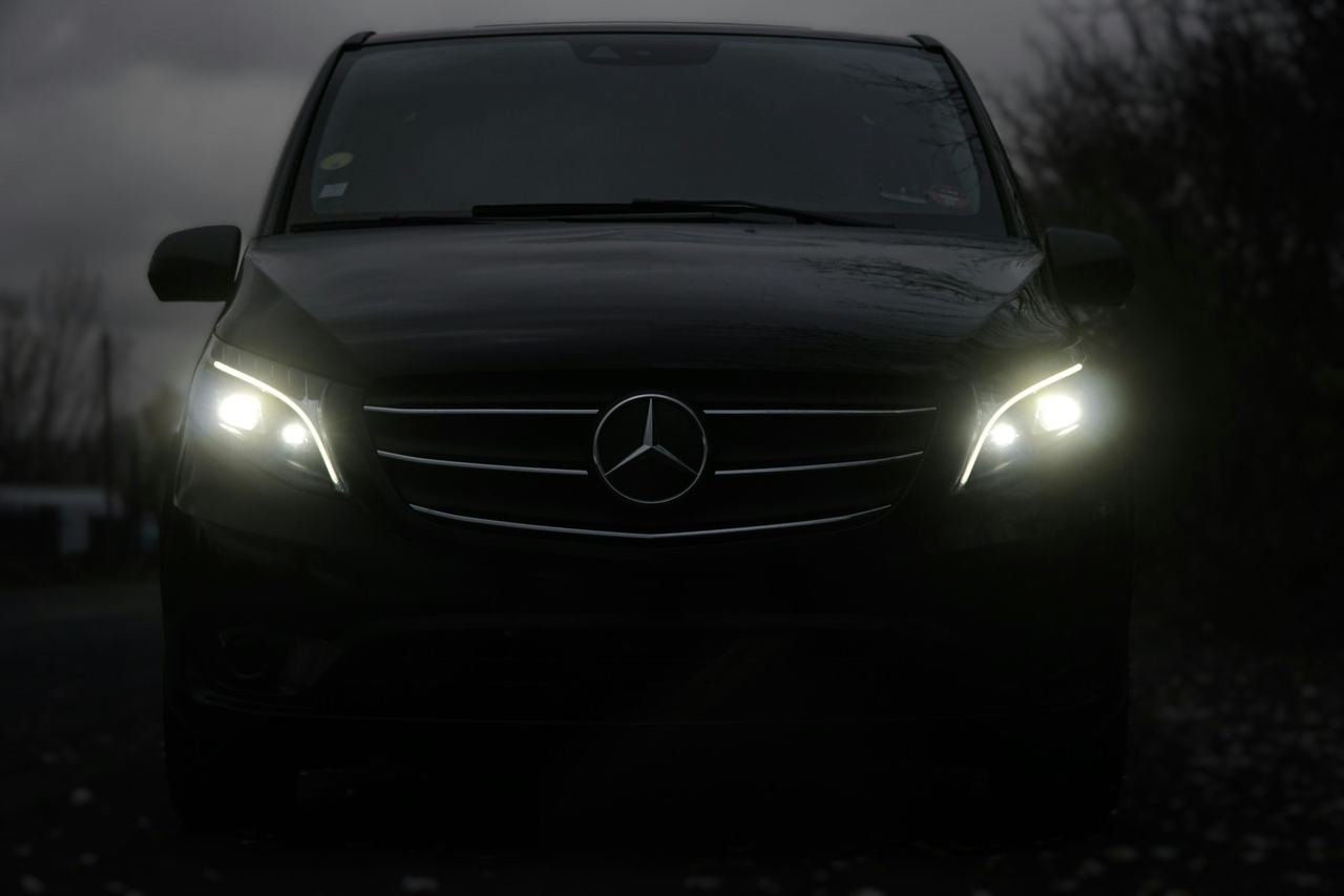 Dark passenger van with headlights on